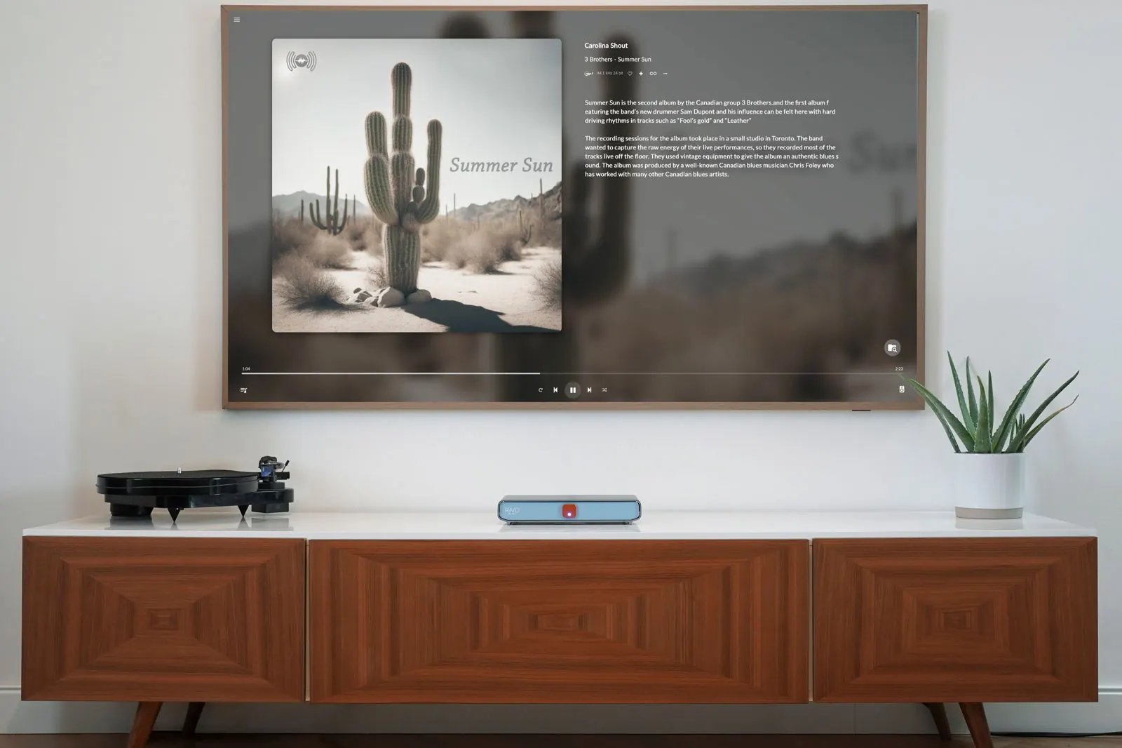 A living room with a TV on the wall showing a cactus album cover and track details, above a wooden sideboard with a turntable and Rivo.