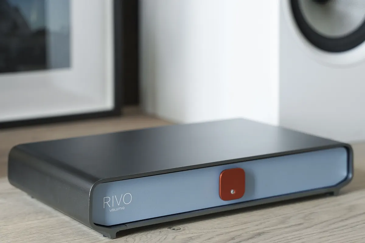 Rivo in the Classic finish on a wooden shelf, next to a framed photo and a white speaker.